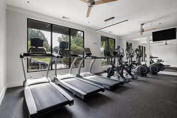 A spacious home gym with treadmills, exercise bikes, and a flat screen TV.